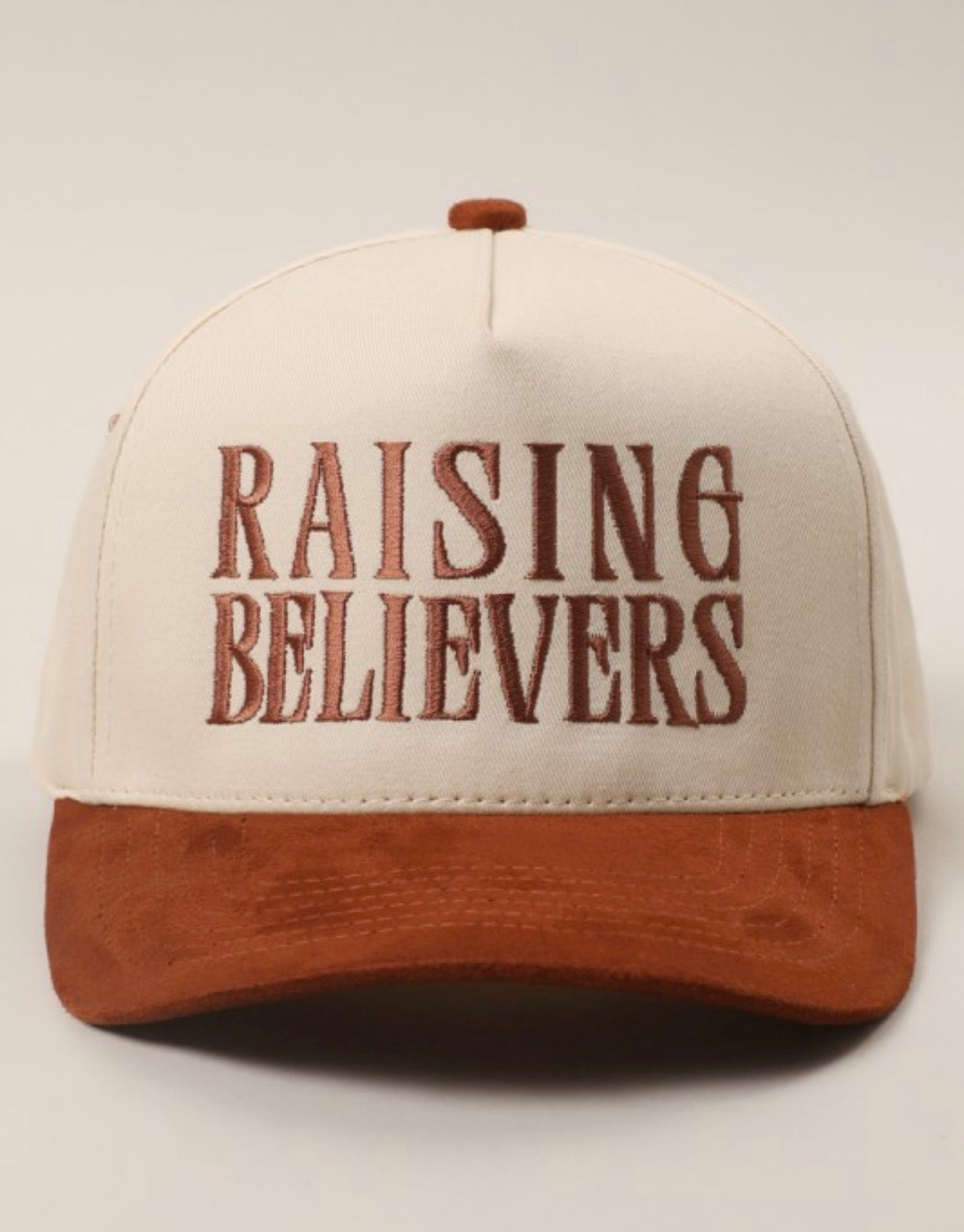 Cap with 'RAISING BELIEVERS' text on a white background