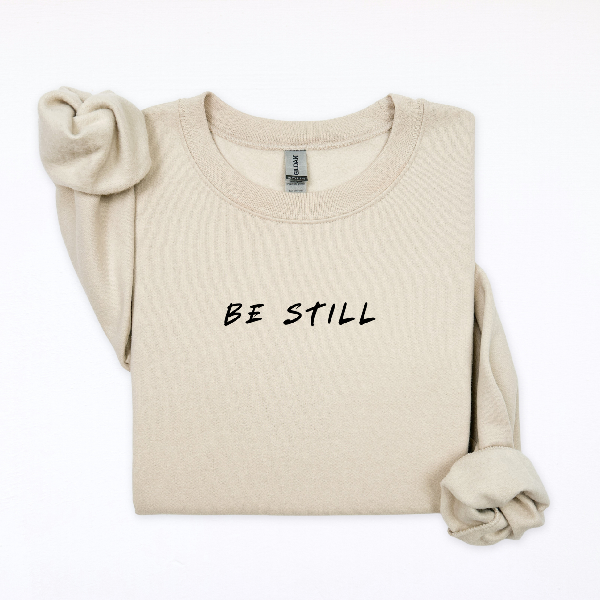 Beige sweatshirt with 'BE STILL' text on a white background